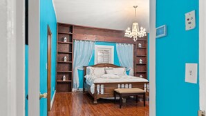 Une chambre à coucher avec un lit en bois, un lustre et un mur bleu.