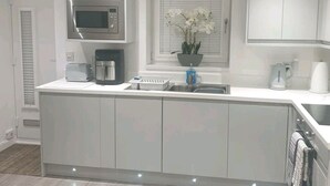 A modern kitchen with a built-in microwave, a coffee machine, and a sink.