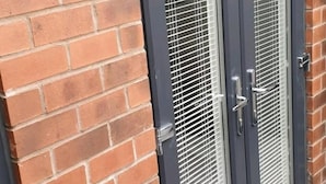 A double door with a metal handle and a keyhole, set in a brick wall with a metal frame.