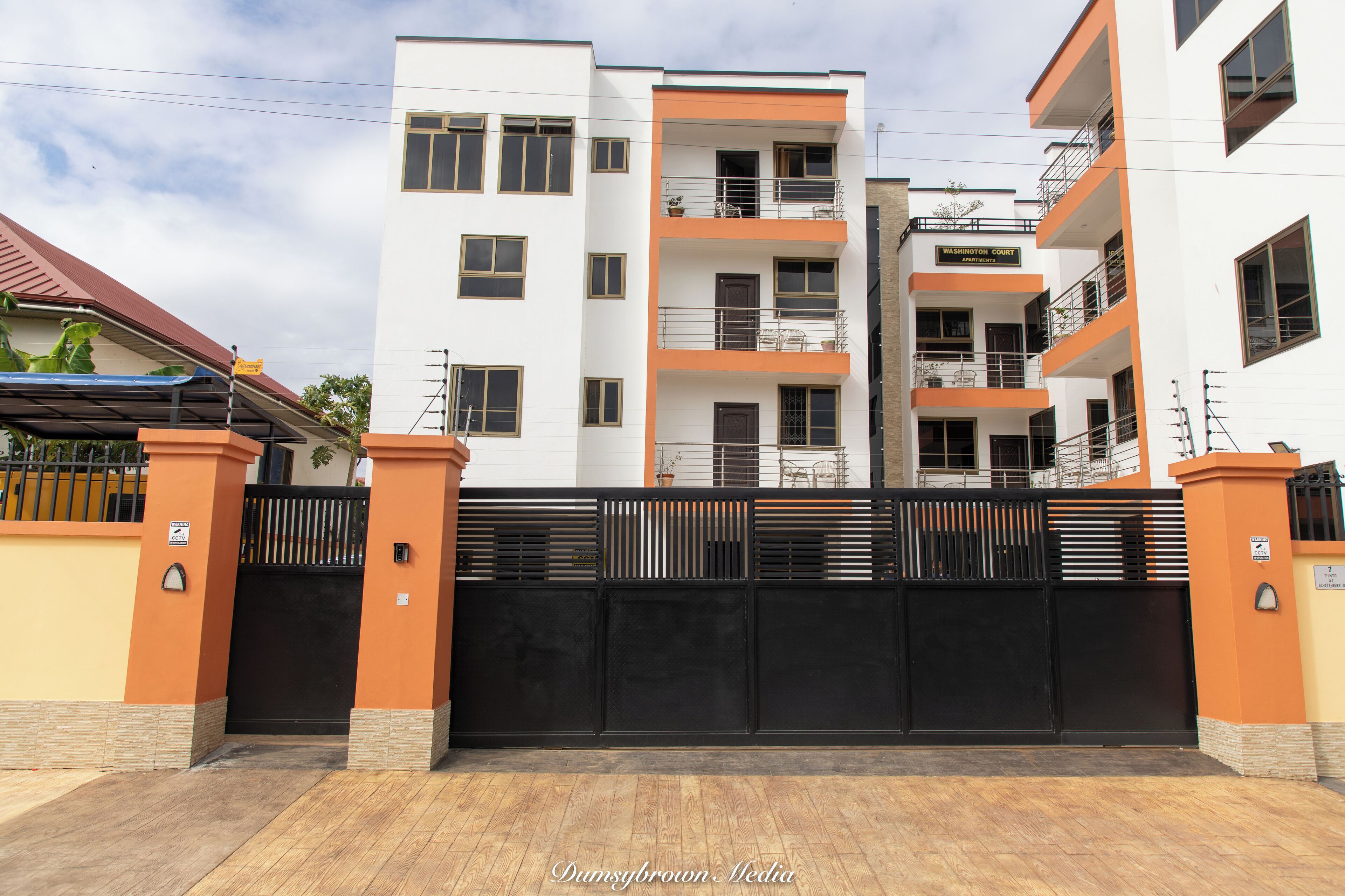 Un edificio residencial de varios pisos con entrada protegida por un portón, balcones y un letrero que dice "Washington Court".