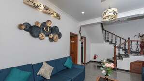 Ein modernes Wohnzimmer mit einem blauen Sofa, Wanddekoration, einer Treppe und einer Deckenleuchte.