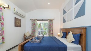 Ein Schlafzimmer mit einem hölzernen Bett, einem Fenster mit Vorhängen, einer Wand-Klimaanlage und Blick auf Palmen.