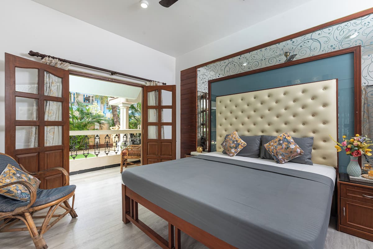 A bedroom with a large bed, wooden furniture, and a view through an open door.