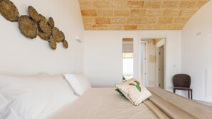 A bedroom with a large bed, a stone ceiling, and a view of the outside. - 2475 Villa Pietra del Sole by Perle di Puglia (Salve)