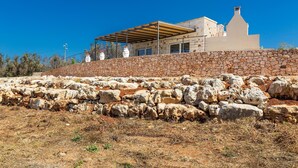A modern house with a stone wall and a wooden pergola. - 2475 Villa Pietra del Sole by Perle di Puglia (Salve)