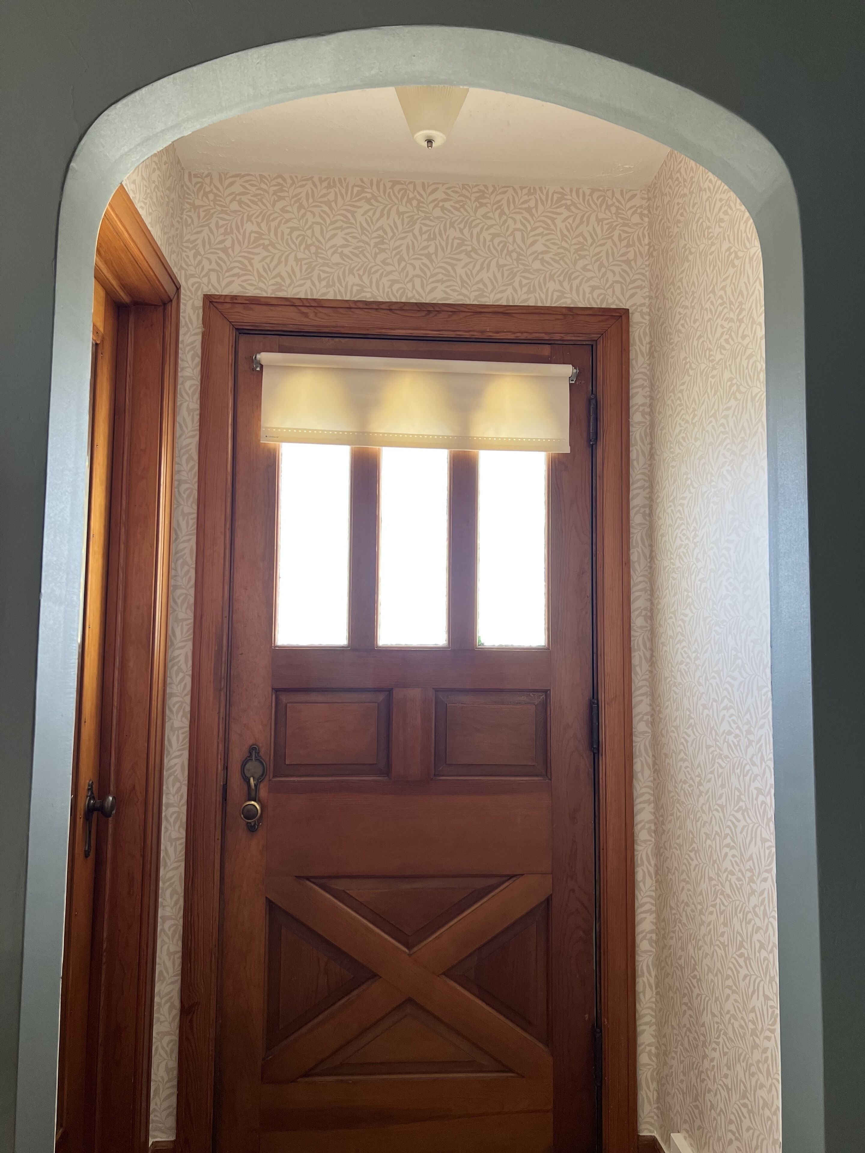 Una puerta de madera con un ventanal y un diseño decorativo en la pared.