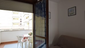 A room with a sliding glass door leading to a balcony with a table and chairs. - Lovely apartment for 6 people with pool, WIFI, A/C, TV, terrace and pets allowed (Rosolina)
