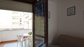 Une pièce dotée d’une porte-fenêtre coulissante donnant sur un balcon avec une table et des chaises.