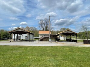 A covered outdoor area with two buildings, a staircase, and a grassy field. - 2 RV spots  full hookup, 30&50 amp sewer & water . In City limits of Sunbright (Sunbright)