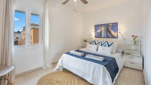 A bedroom with a bed, a ceiling fan, a window with curtains, and a painting on the wall. - Next to the SANLUCAR BARRAMEDA swimming pools (Sanlúcar de Barrameda)