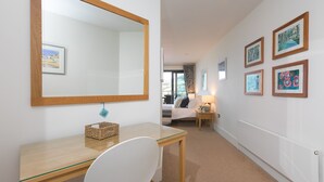 Habitación de hotel con escritorio de madera, un espejo grande y una cama con vistas.
