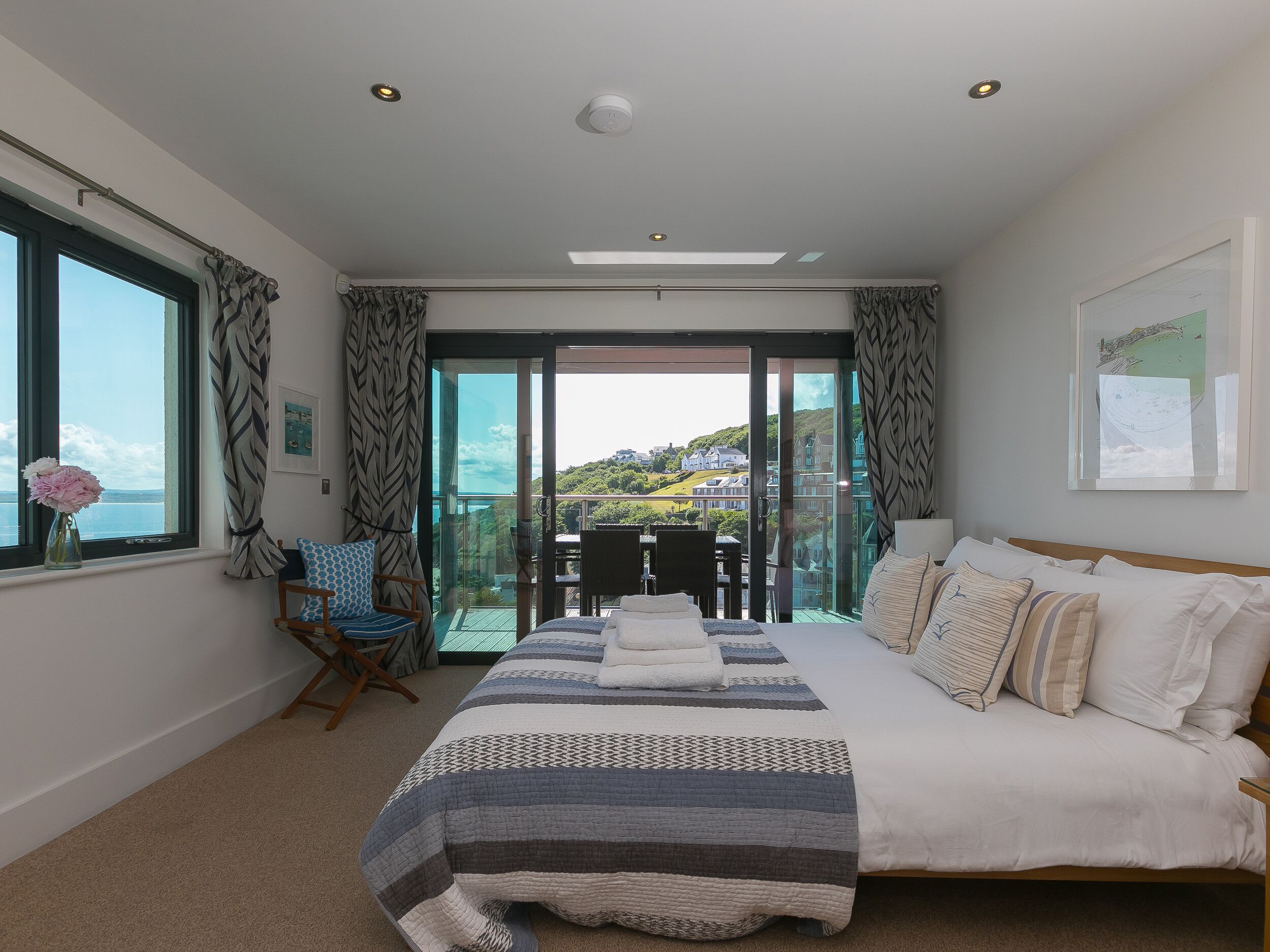 A bedroom with a large bed, a view of a balcony, and a window with curtains.
