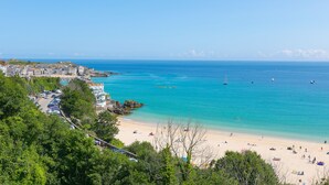 Un pueblo costero con playa, mar azul cristalino y una mezcla de edificios residenciales y comerciales.