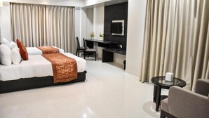 A modern hotel room with a large bed, a desk, and a small table. - Hotel Platinum Shravasti (Ikauna)