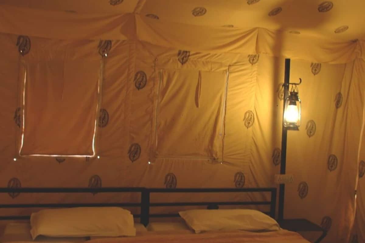 A room with a bed, a window, and a wall-mounted lamp.