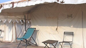 A tent with a number '105' on the wall, two folding chairs, and a small table. - Camp Thar Osian (Jodhpur)