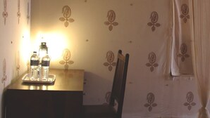 A room with a wooden desk, two water bottles, a chair, and a patterned wall. - Camp Thar Osian (Jodhpur)
