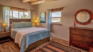 Un dormitorio con una cama de madera, una mesita de noche con lámpara, un aparador y un espejo con marco decorativo.