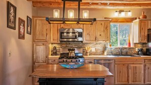 Una cocina con armarios de madera, una isla central, estufa, microondas y ventana con vistas.
