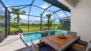 A covered outdoor area with a pool, wicker furniture, and a table with fruit.