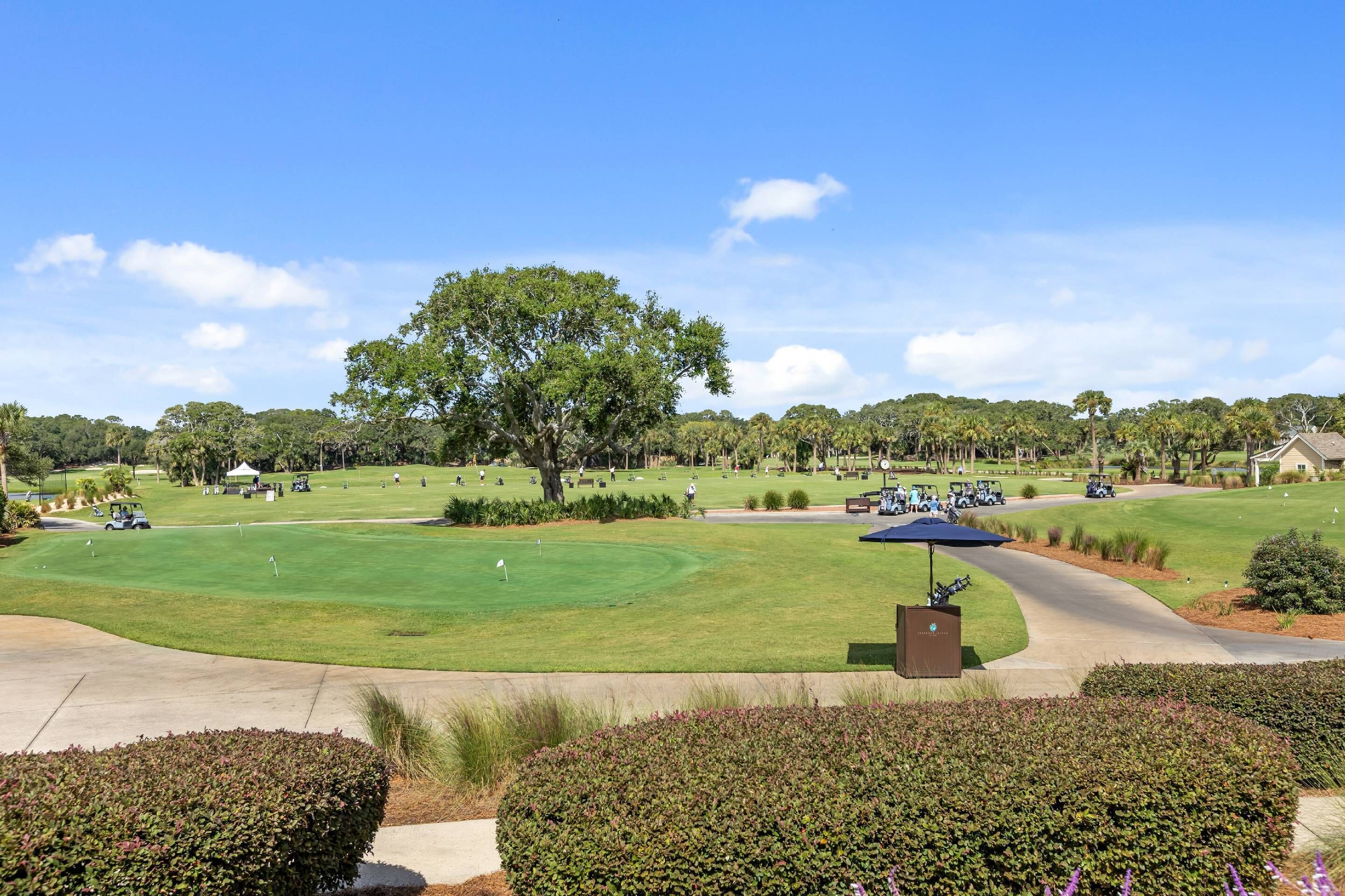Un campo de golf con un árbol grande, un pabellón y un césped bien cuidado.