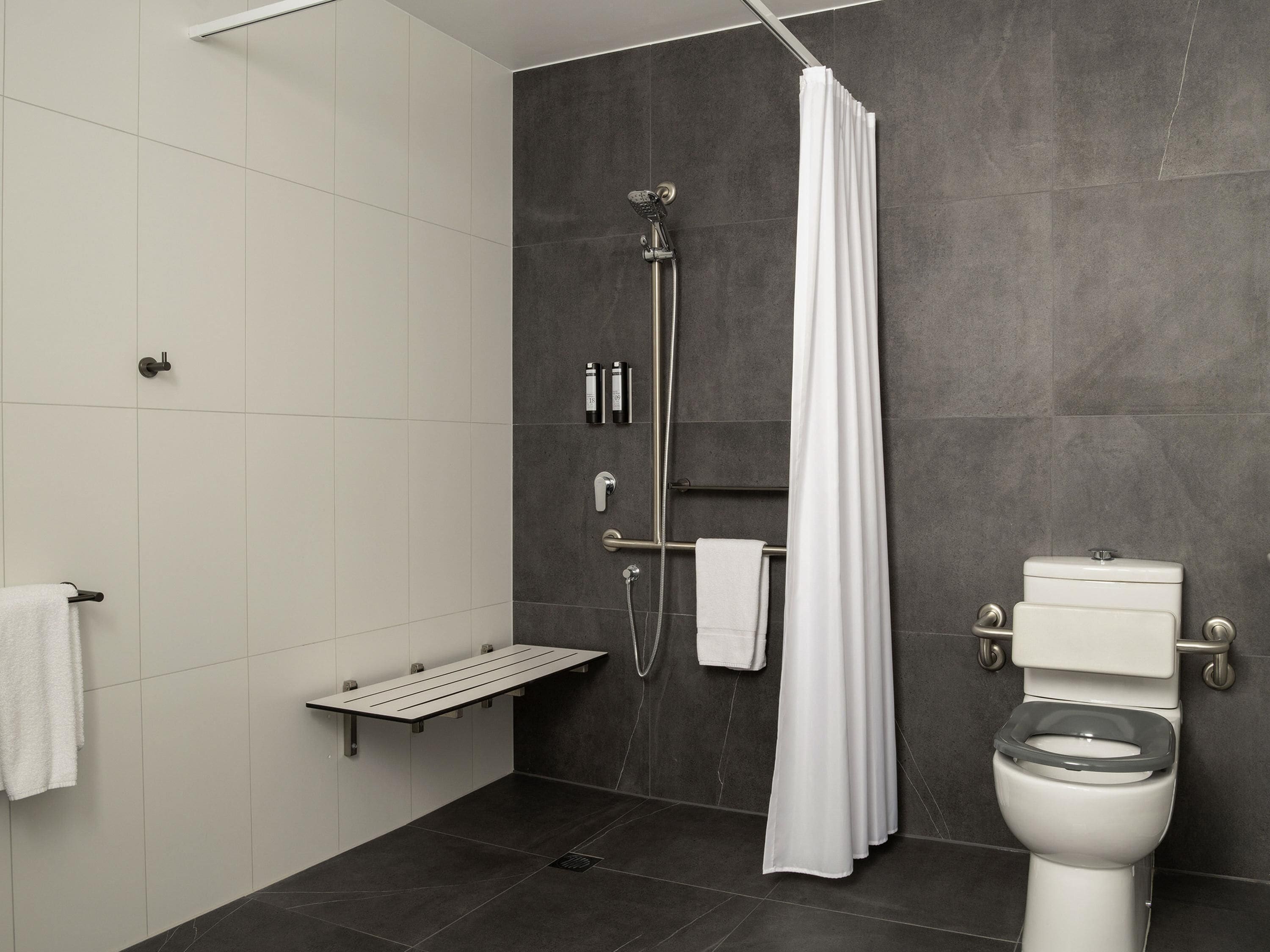 A modern bathroom with a shower, toilet, and towel rack.