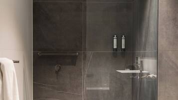 A modern bathroom with a glass-enclosed shower, a white toilet, and a vanity with a mirror.