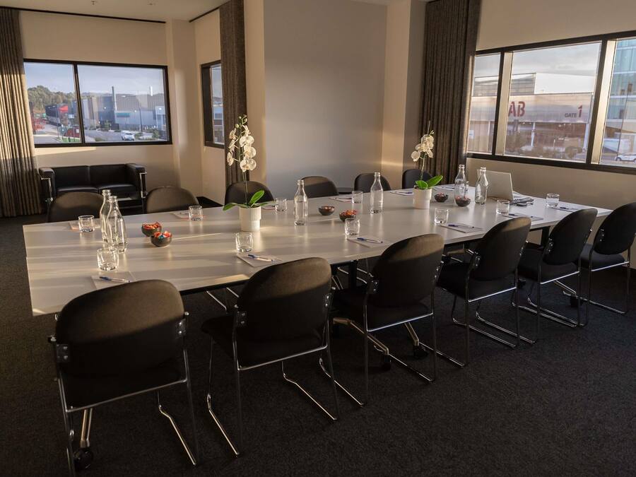 A conference room with a long table, chairs, and a laptop.