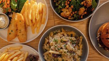 A table with various dishes including fish and chips, pasta, salad, and a burger.