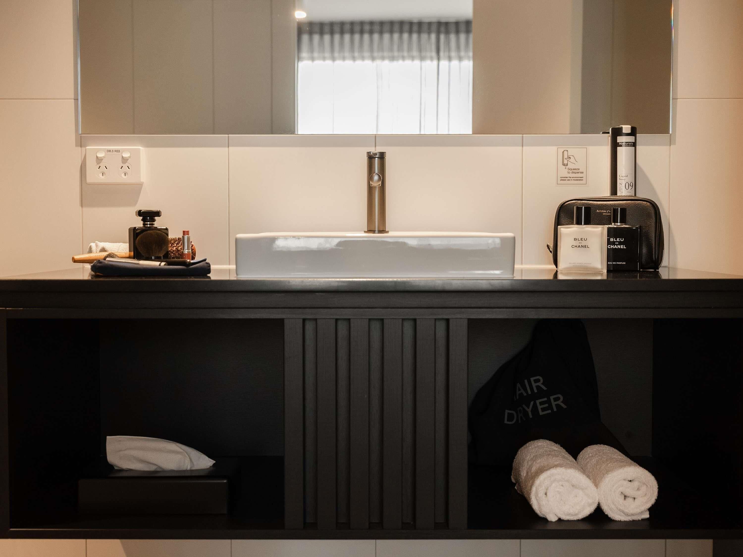 Een moderne badkamer met een grote spiegel, een wastafel en een handdoekhouder.