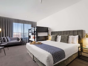 Habitación de hotel con literas, un sofá, un escritorio y vistas a la ciudad.