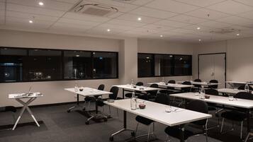 A conference room with tables, chairs, and a projector screen.