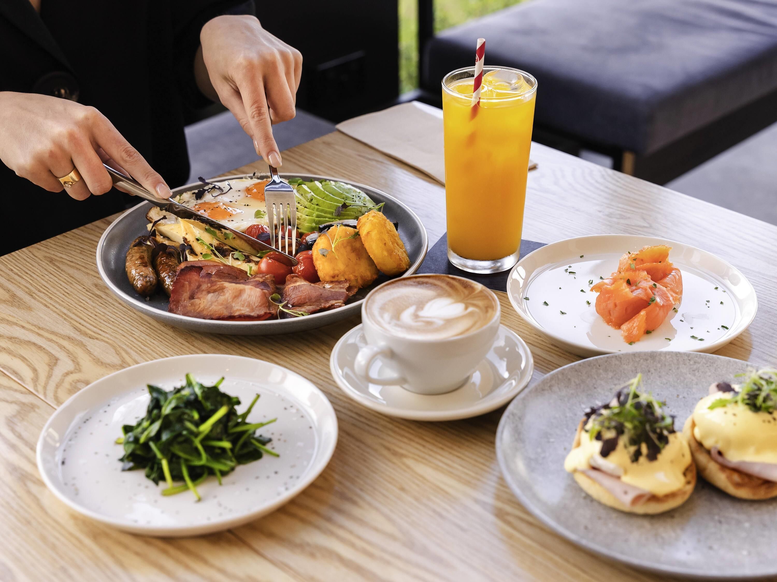 A table with various dishes, a glass of orange juice, and a cup of coffee.