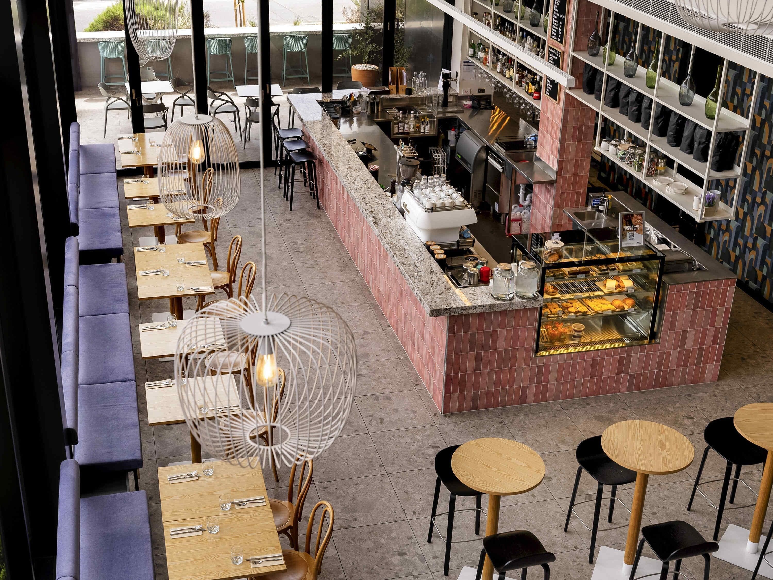 A restaurant with multiple seating areas, a bar, and a display case with food items.