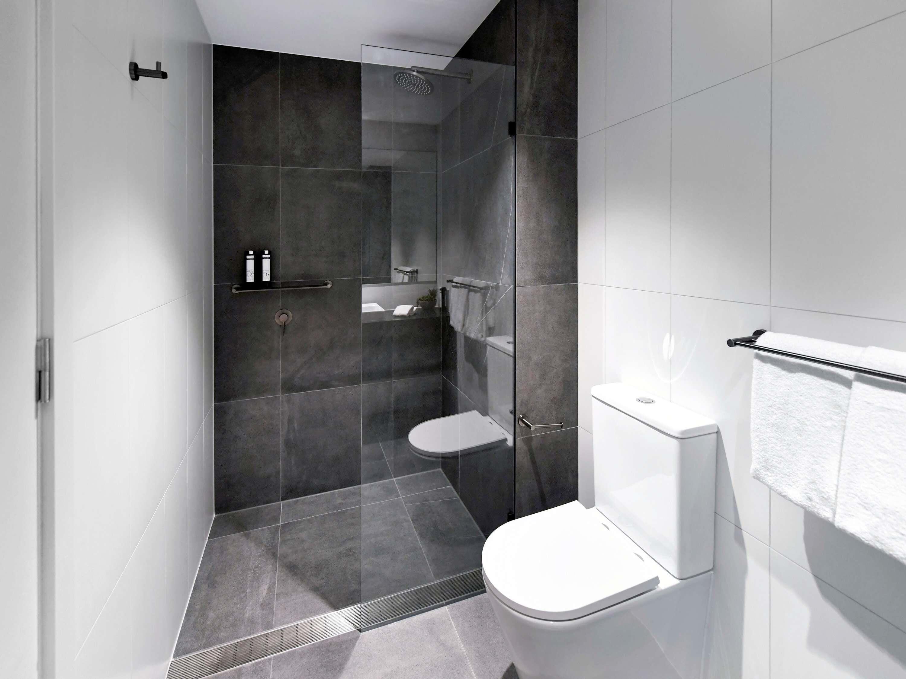 A modern bathroom with a glass-enclosed shower, a white toilet, and a towel rack.