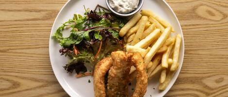 A plate with fish and chips, a salad, and a small bowl of sauce.