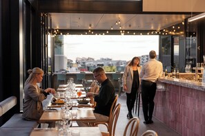 Un restaurant doté d’une terrasse, d’un bar et offrant une vue sur le paysage urbain.