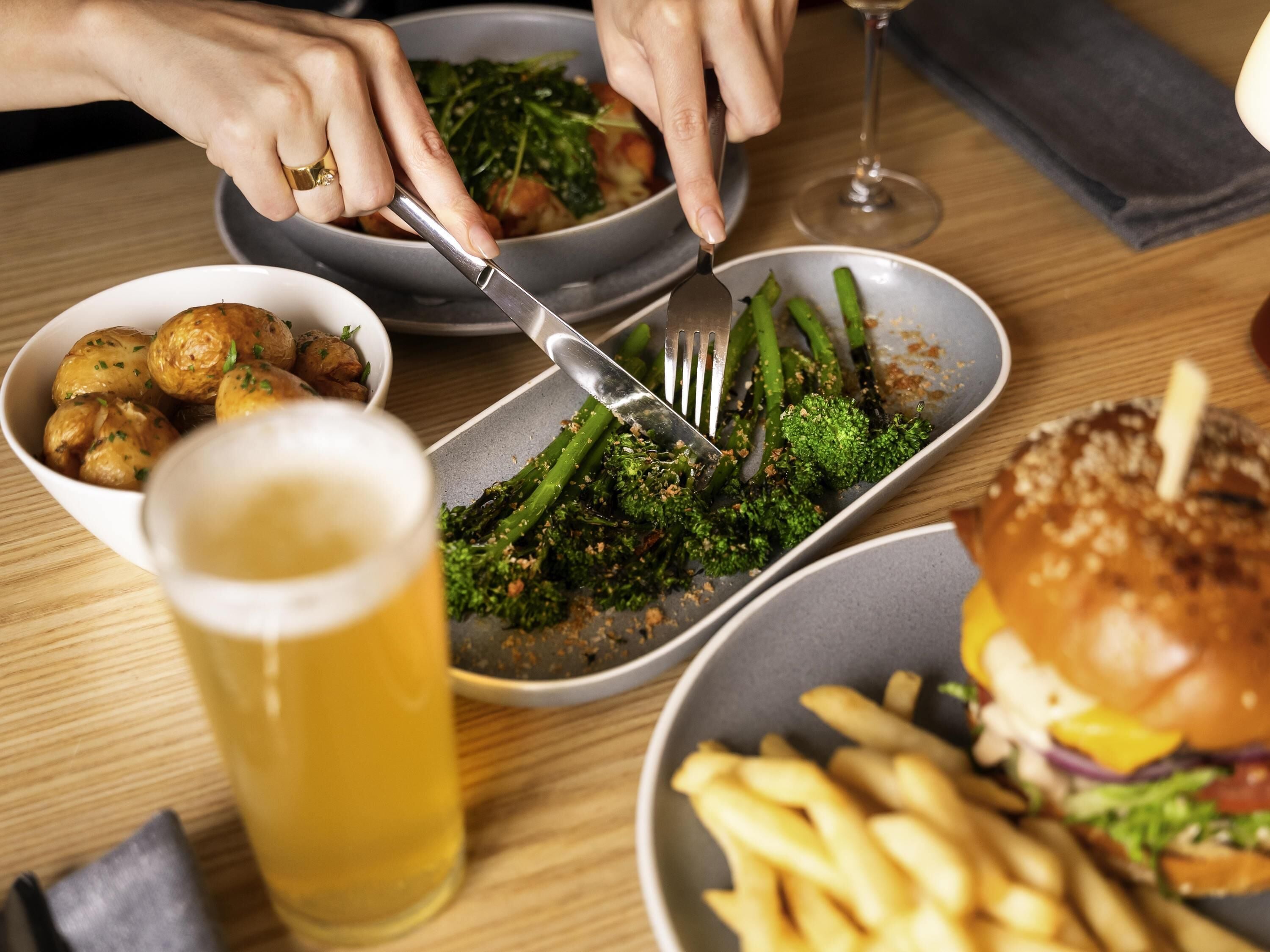 Ein Esstisch mit einem Teller Essen, einem Bierglas und einem Burger.