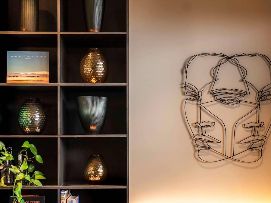 A bookshelf with decorative vases and a framed abstract artwork.