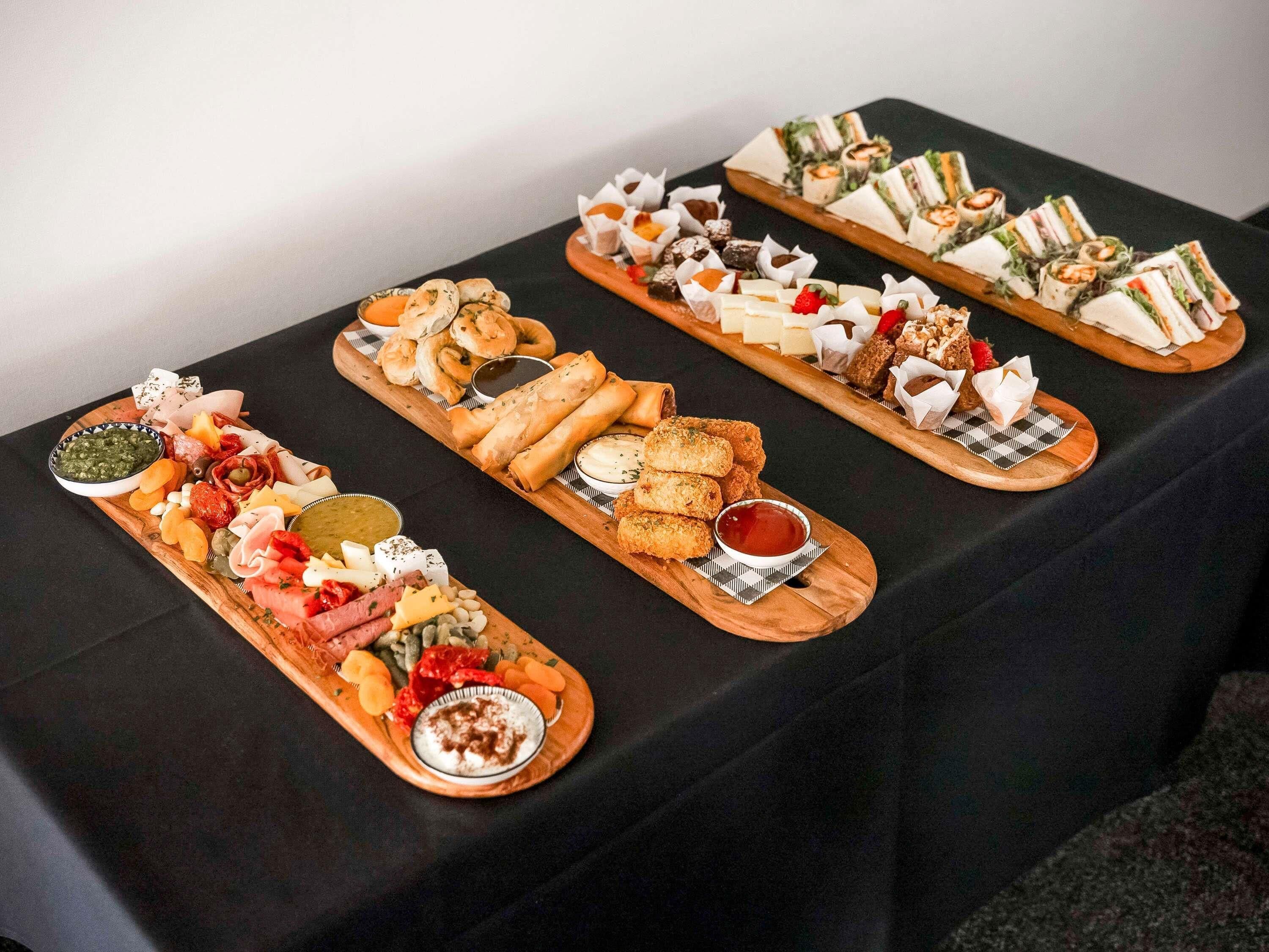 A table with various food platters, including cheeses, meats, and pastries.