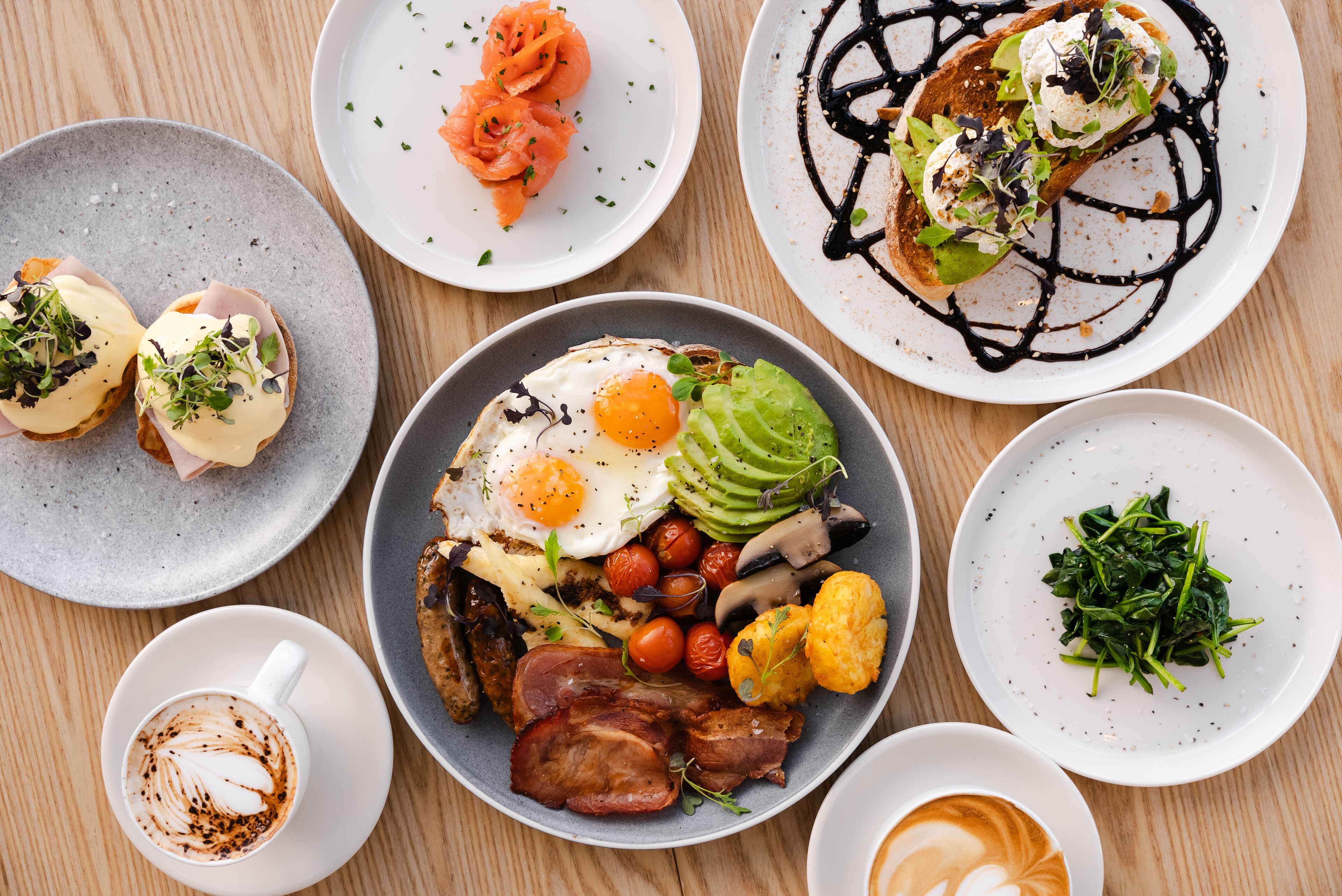 Verschiedene Frühstücksgerichte, darunter Eier, Speck, Avocado und Räucherlachs.