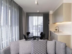 Una sala de estar moderna con un sofá, un cojín estampado y un comedor con sillas.