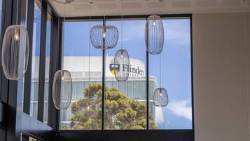 A modern interior with large windows, hanging pendant lights, and a view of a building with the name 'Flinders'.