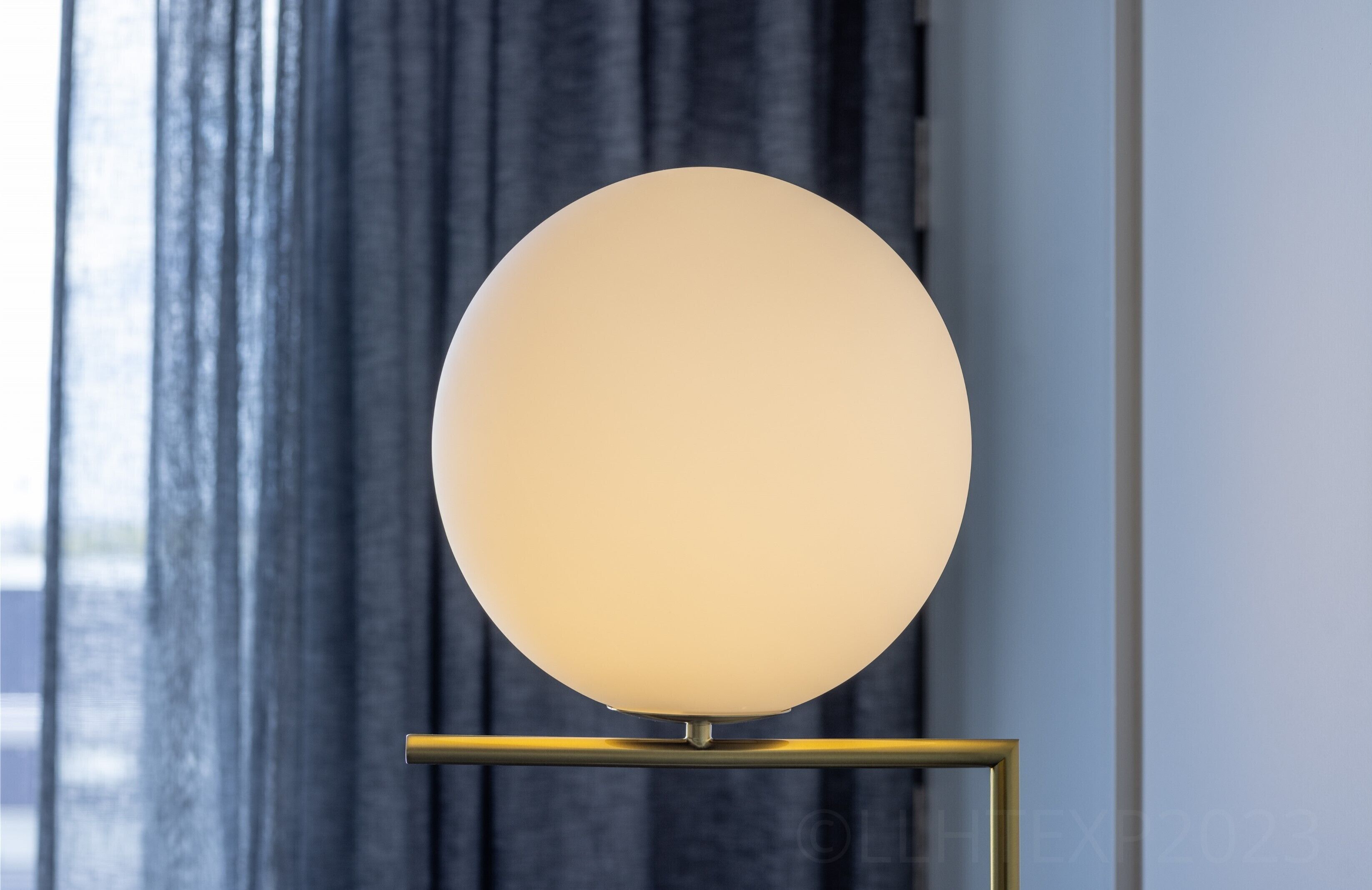 Een ronde, verlichte wandlamp op een gouden voet.