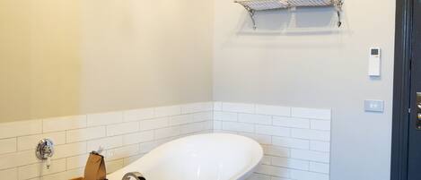 A bathroom with a freestanding bathtub, a wooden bath tray, a towel rack, and a patterned floor.