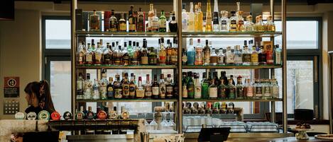 Un bar avec plusieurs étagères remplies de bouteilles d’alcool, une caisse enregistreuse et un comptoir.