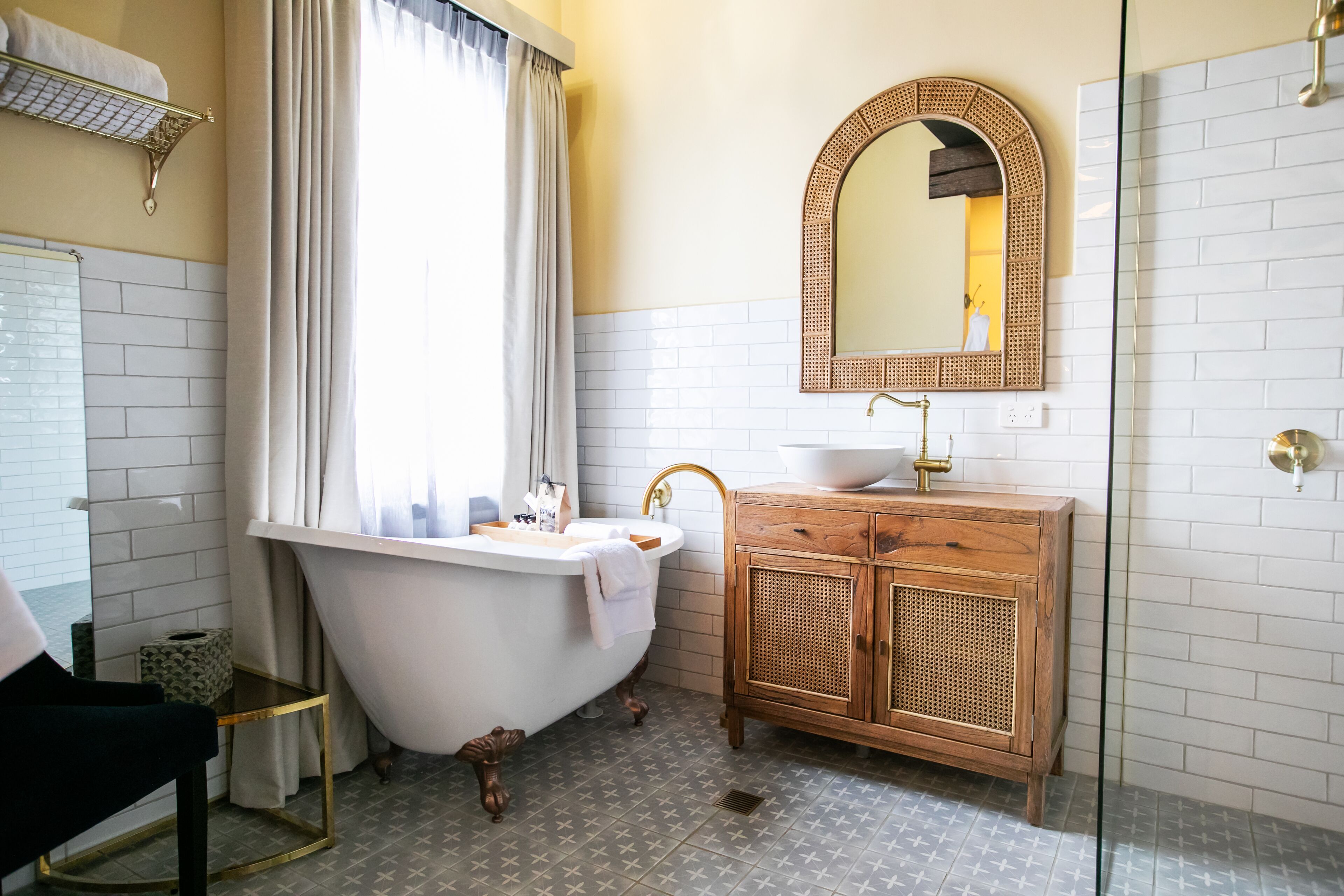 A bathroom with a freestanding bathtub, a wooden vanity, a mirror, and a towel rack.