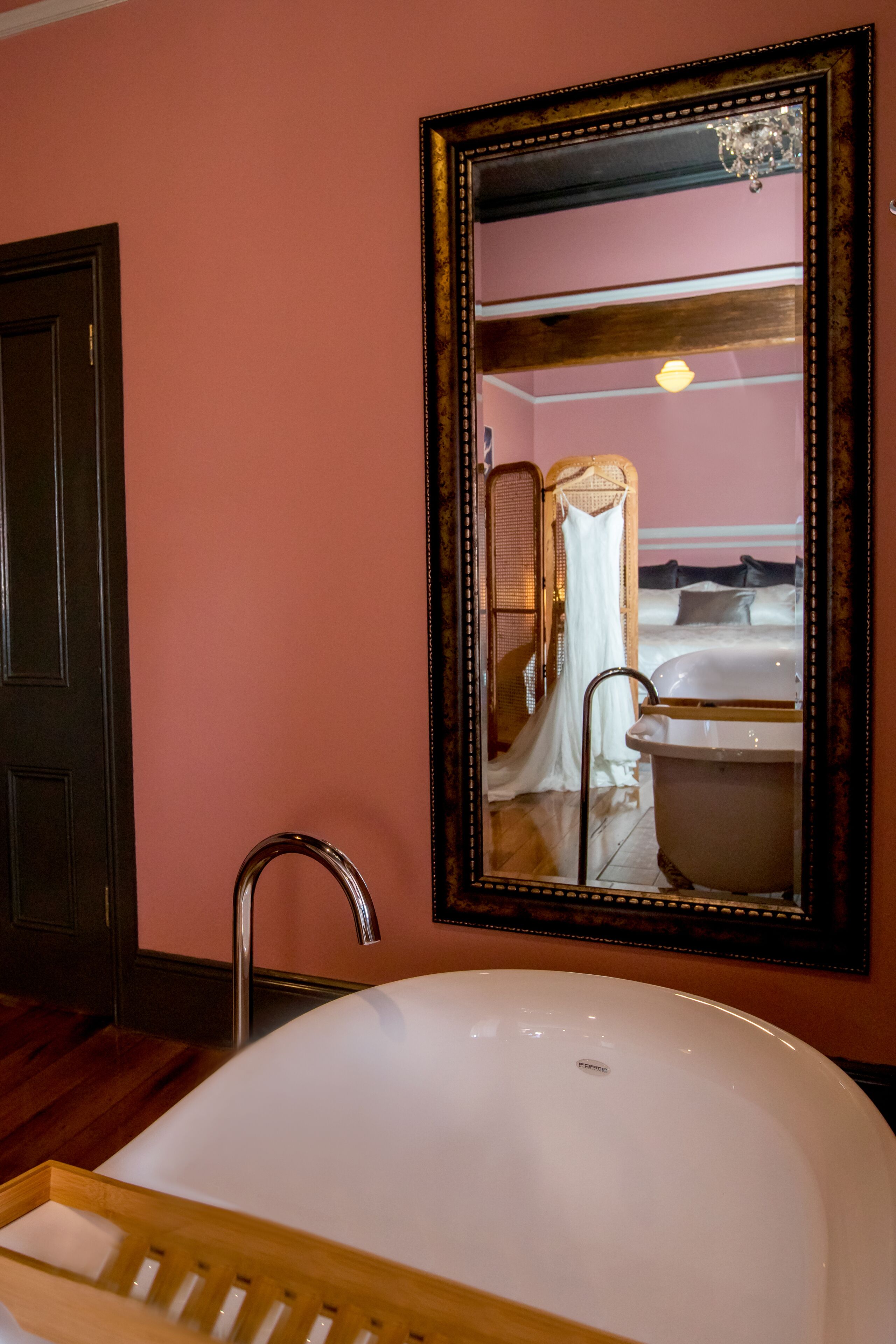 Une salle de bain avec un grand miroir, une baignoire et une chaise en bois.