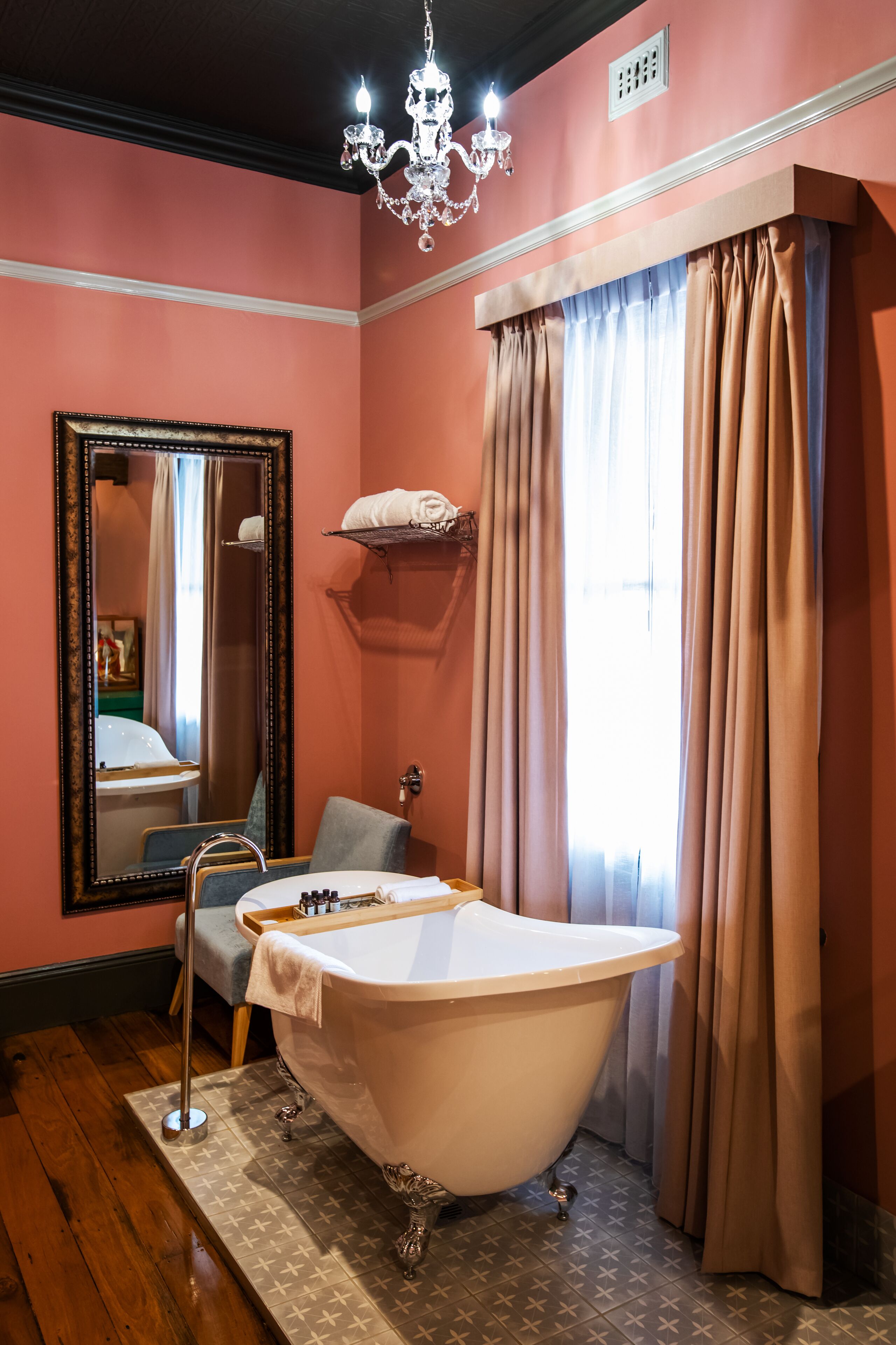 A bathroom with a freestanding bathtub, a large mirror, and a chandelier.