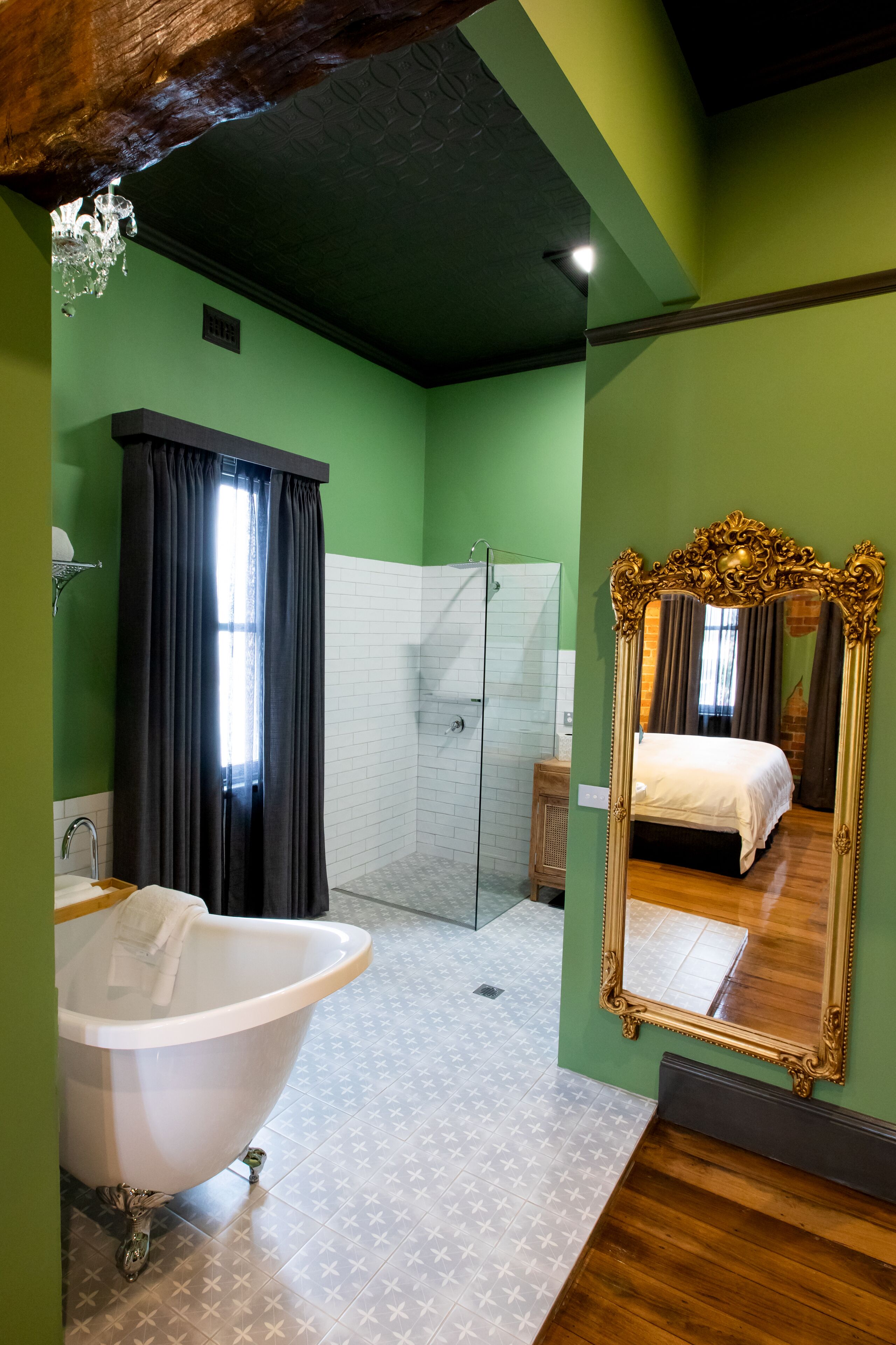 Une salle de bain dotée d’une baignoire sur pieds, d’une douche et d’un grand miroir orné d’un cadre travaillé.